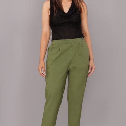Woman wearing green pants and a black top on a gray background